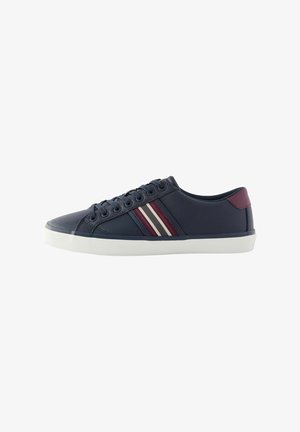 Sneaker en cuir bleu avec semelle blanche, présentant trois bandes horizontales en rouge, blanc et bordeaux ; lacets ronds et design profil bas.