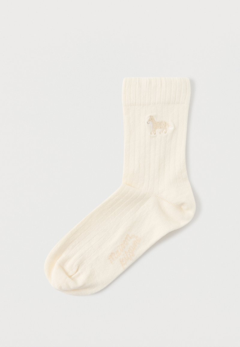 Κρεμ κάλτσα ριπ με μικρή κεντημένη λεπτομέρεια αλόγου κοντά στο πάνω μέρος της μανσέτας, τοποθετημένη επίπεδα σε λευκή επιφάνεια.