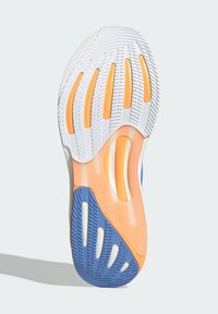 Suela de zapato con tacos de goma blanca, naranja y azul, que presenta patrones de agarre texturizados para tracción y flexibilidad.