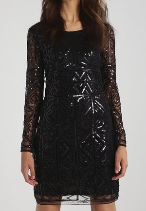 Vestido negro hasta la rodilla con mangas largas transparentes, decorado con patrones geométricos de lentejuelas y escote redondo.