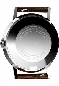 Boîtier de montre en acier inoxydable avec un dos argenté poli, bracelet en cuir marron et détails gravés comprenant "Mouvement à remontage manuel" et "Timex."