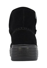 Stivaletto alla caviglia in camoscio nero con punta arrotondata, cuciture strutturate lungo la cucitura e suola spessa in gomma con scanalature orizzontali.