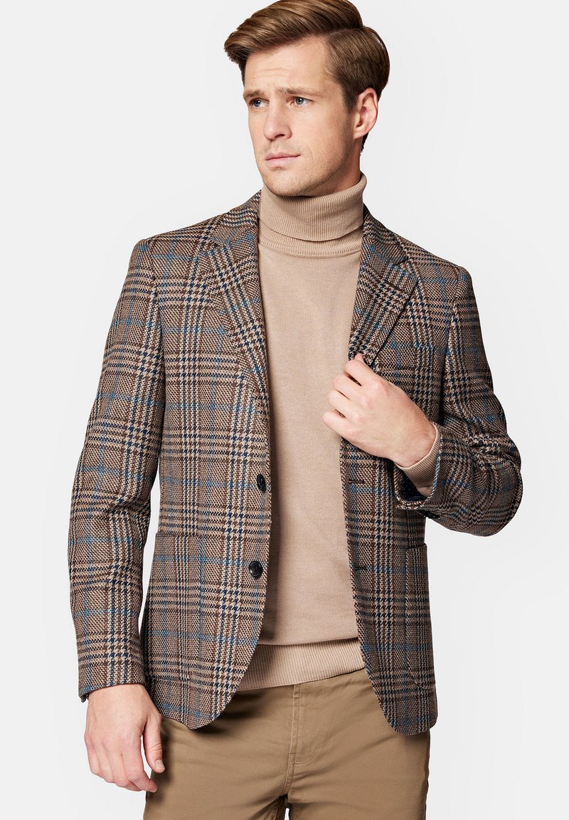 Brązowa marynarka w kratę z niebieskimi akcentami, szpiczaste klapy, dwa guziki i teksturowana tkanina, noszona na beżowym swetrze z wysokim kołnierzem.