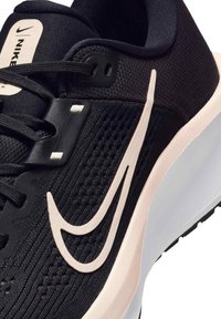 Mustat urheilukengät, joissa on teksturoitu verkko-yläosa, vaaleanpunaiset yksityiskohdat ja valkoinen pohja; kengissä on suuri swoosh-logo ja nauhakuosi.