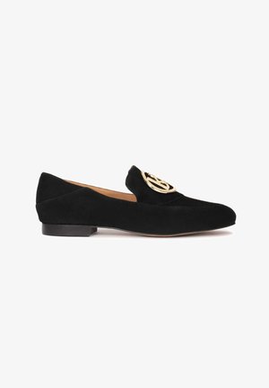 Mocassin plat en daim noir avec bout arrondi et boucle circulaire dorée sur le dessus, avec un petit talon et une doublure intérieure couleur fauve.