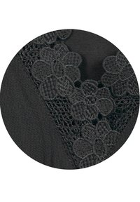 Svart tyg med blommig svart broderi med intrikat detaljer och en texturerad yta, som visar en lager-på-lager-design.