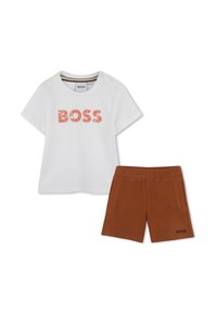 T-shirt bianca con la scritta "BOSS" in lettere arancioni testurizzate, abbinata a pantaloni corti marroni con tasche laterali e "BOSS" ricamato sull'orlo.