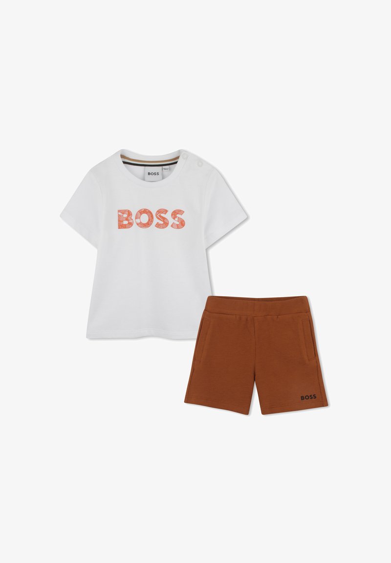 T-shirt bianca con la scritta "BOSS" in lettere arancioni testurizzate, abbinata a pantaloni corti marroni con tasche laterali e "BOSS" ricamato sull'orlo.