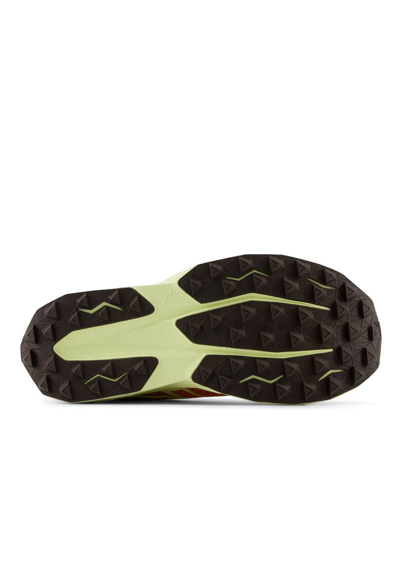 Semelle de chaussure avec un motif en caoutchouc texturé noir et une semelle intercalaire vert clair. Présente des crampons angulaires et triangulaires pour une traction optimale.
