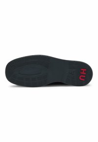 Schwarze Gummisohle mit strukturiertem Grip-Muster. Verfügt über das rote "HU"-Branding auf der rechten Seite. Glatte, flache Oberfläche mit rechteckigen Profilen.