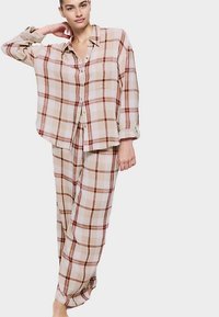 Beige geruit pyjamaset bestaande uit een losvallend overhemd met knopen en lange mouwen, en een broek met wijde pijpen. Het materiaal lijkt zacht en lichtgewicht.