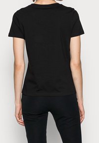 Sort bomulds t-shirt med korte ærmer, rund halsudskæring og en glat tekstur. Designet til en tætsiddende silhuet, vist fra ryggen.