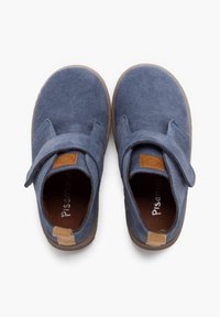 Scarpe di camoscio blu con una texture morbida, cinturino in velcro, suole in gomma marrone e un piccolo accento beige sul tallone. Presentano cuciture visibili.