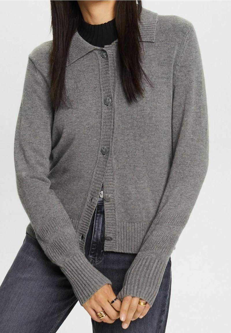 Šedý kardigan s knoflíkovým zapínáním vpředu, žebrovanými manžetami a límcem. Vyrobený z měkkého materiálu, s přiléhavým střihem a texturovanými detaily.