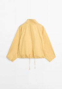 Hellgelbe Langarmjacke mit hohem Kragen und verstellbarem Kordelzug am Saum, von hinten vor weißem Hintergrund gezeigt.
