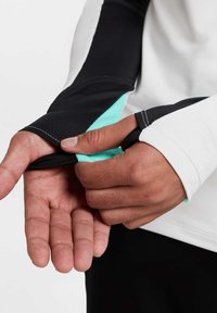 Langärmliges Sportshirt mit schwarzen, weißen und türkisfarbenen Abschnitten; Daumenlöcher; eleganter, dehnbarer Stoff; figurbetontes Design.