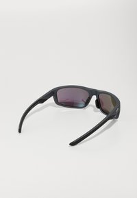 Lunettes de soleil noires avec une finition mate, design enveloppant, verres polarisés avec teinte dégradée, et embouts de branches en caoutchouc pour une meilleure prise.