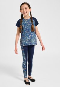 Aktivkläder för ungdomar som består av en blommönstrad blå topp med korta ärmar och matchande blå leggings med blommiga sidodetaljer.