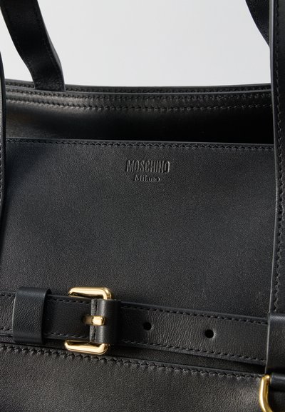 Μαύρη δερμάτινη τσάντα με λουριά ραμμένα, λεπτομέρεια ζώνης με χρυσή αγκράφα και ανάγλυφο λογότυπο "Moschino Milano" στο μπροστινό μέρος.