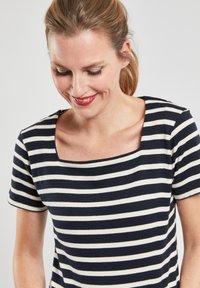 Haut à rayures bleu marine et blanc à manches courtes avec un décolleté carré ; il présente un tissu doux et élastique ainsi qu'une silhouette ajustée.