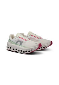 Witte sportieve schoenen met roze accenten, textuur bovenkant, comfortabele, wolkenachtige zool en opvallende "CLOUDTEC" branding aan de zijkanten.