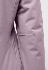 Blazer viola chiaro con tessuto testurizzato, caratterizzato da un design lineare e un discreto dettaglio della tasca laterale. Superficie liscia, vestibilità su misura.