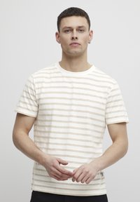 Stripet t-skjorte med korte ermer i lys beige med kremfargede striper, laget av myk bomull, med rund hals og rett passform.