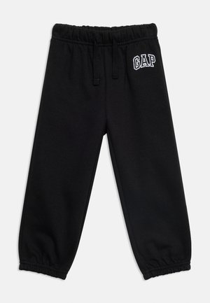 Pantalon de jogging noir à taille élastique avec cordon de serrage et poignets élastiques, avec un logo blanc "GAP" sur le haut de la cuisse gauche.