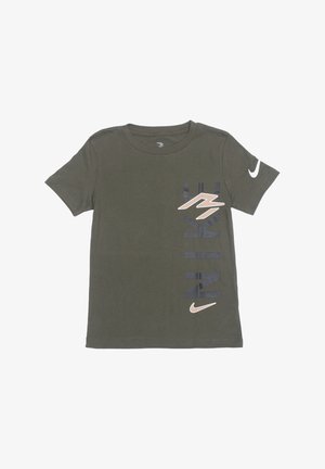 T-shirt Nike manches courtes vert olive avec texte "NIKE" noir vertical, logos Swoosh beige sur la poitrine et la manche gauche.