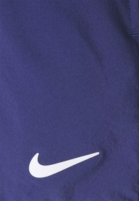 Lila Nike-shorts med en framträdande vit logotyp, tillverkade av ett slätt och lätt tyg med en diskret struktur.