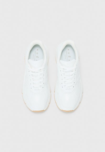Sneaker bianchi da uomo con una superficie liscia e lucida, dotate di lacci rotondi, linee curve e una suola in gomma naturale.