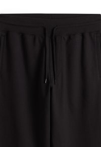 Schwarze Jogginghosen aus weichem Material, mit verstellbarem Kordelzugbund, zwei Seitentaschen und einer glatten Textur.