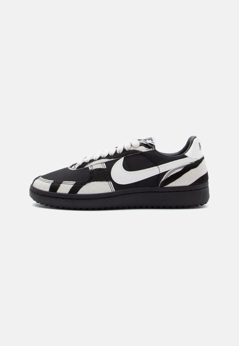 Sneaker in bianco e nero con tomaia texture, caratterizzate da un prominente logo Nike bianco e un battistrada nero, chiusura con lacci e dettagli a motivo.