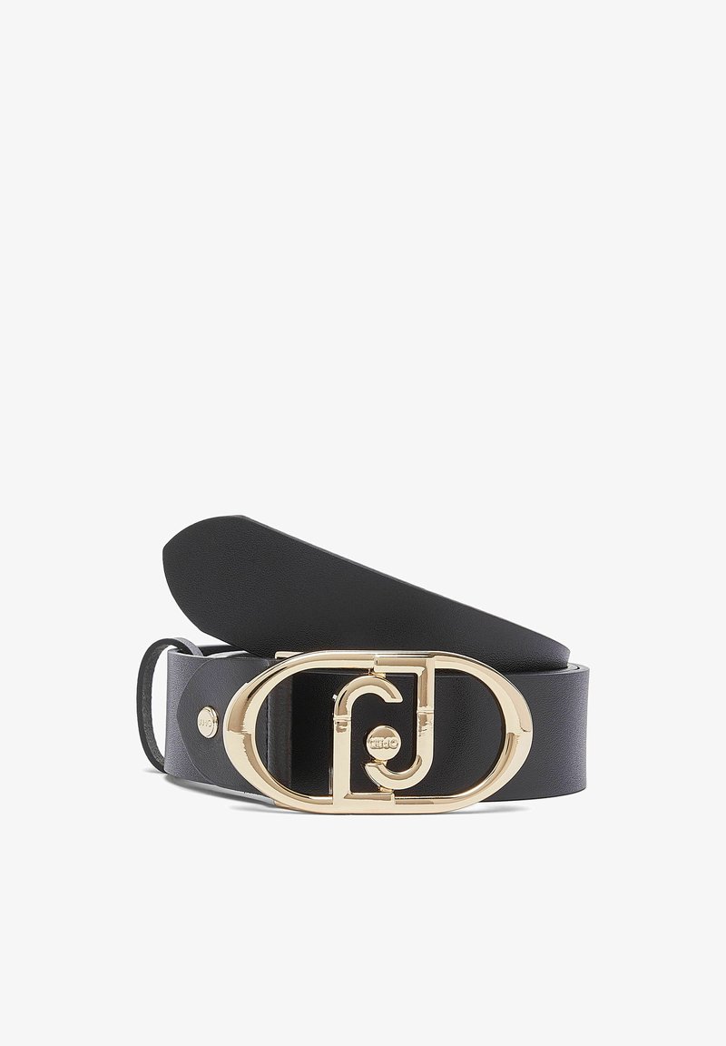 Ceinture en cuir noir avec une grande boucle ovale dorée présentant un motif géométrique entrelacé sur fond blanc.