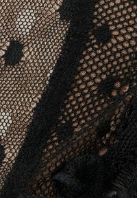 Zwarte gaasstof met hexagonale en stippenpatronen, gelaagd over een naakte basis. Bevat delicate kantafwerkingen en een gestructureerd oppervlak.