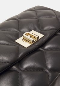 Czarna pikowana skórzana kopertówka ze złotym zapięciem, o gładkiej fakturze i wzorze w kształcie diamentów, oferująca elegancki design.