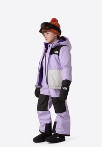 Μωβ και μαύρο μπουφάν χιονιού με ταιριαστό παντελόνι, που διαθέτει ένα λευκό πάνελ. Διακοσμημένο με γάντια και καπέλο με πολύχρωμο πομ πον.