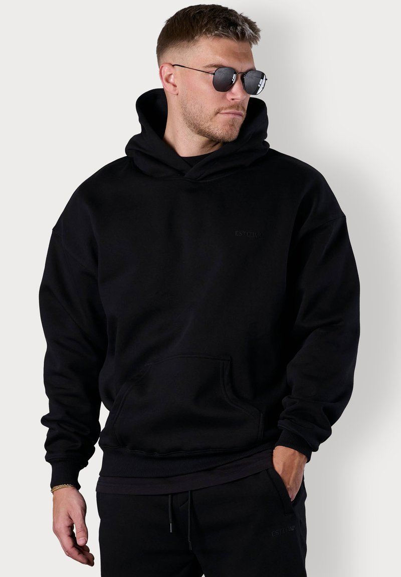 Black hooded sweatshirt made of fleece fabric, featuring a front kangaroo pocket, ribbed cuffs, and a minimal embossed logo.