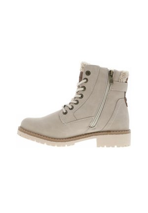 Bottine beige avec un laçage à l'avant, œillets en métal et zip sur le côté. Elle présente une doublure en fourrure texturée et une semelle en caoutchouc avec traction.
