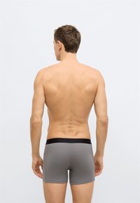 Γκρι μπόξερ με μαύρη μέση, κατασκευασμένα από απαλό ύφασμα. Το σχέδιο διαθέτει εφαρμοστή γραμμή και λεία υφή.