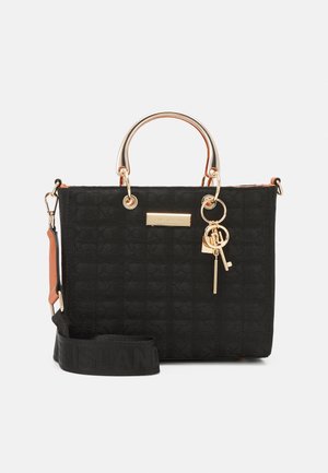 Bolso negro texturizado con asas metálicas doradas, llavero decorativo y correa negra desmontable sobre fondo blanco.