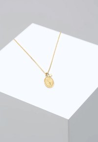 Guldkæde med en oval vedhæng med reliefdesign og en lille stjernecharme, vist mod en minimalistisk baggrund.