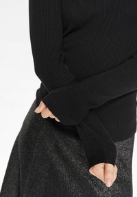 Czarny żebrowany sweter z długimi rękawami, z otworami na kciuki. Miękka faktura, dopasowany krój, zestawiony z fakturowaną czarną spódnicą.