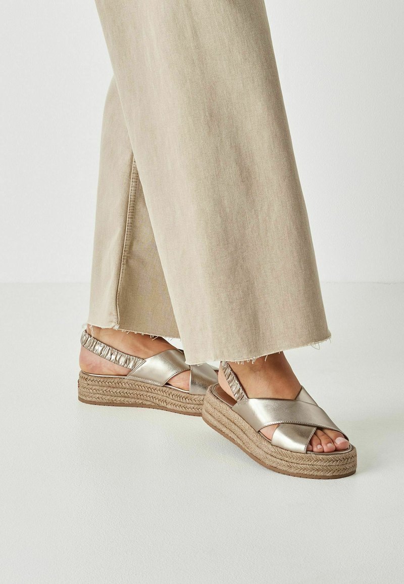 Metallicguld kilehøje sandaler med krydsede stropper og en flettet jute-sål. Har en rynket bagstropp for ekstra komfort.