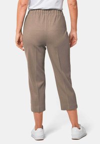 Bruine, ribbelige, elastische cropped pants met een ontspannen pasvorm, gecombineerd met witte sneakers. Eenvoudig ontwerp zonder zichtbare patronen of accenten.