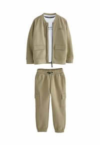 Khaki dvojdielny outfit obsahuje bomber bundu na zips s náprsnými vreckami a biely tričko, doplnené zodpovedajúcimi cargo nohavicami.