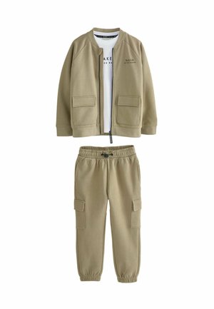 Khaki kahest osast koosnev komplekt sisaldab lukuga bomber-jakki, millel on plaastrikotid, ja valget T-särki, mis on sobitatud vastava tooni cargo-pükstega.