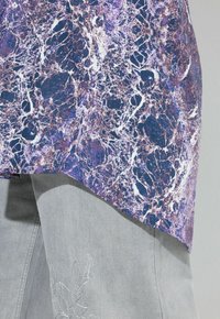 Paarse en marineblauwe gemarmerde top met een afgeronde zoom, gecombineerd met grijze broek met bloemenborduursel in zilver. Textuurstof.