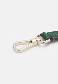 Zielony pasek ze skóry z srebrnym metalowym zaciskiem o fakturowanym wykończeniu i wygrawerowanym logo. Gładkie krawędzie i solidne elementy sprzętowe.