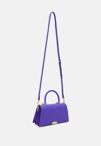 Fioletowa torebka o strukturalnym kształcie, wykonana z gładkiego materiału. Posiada krótki uchwyt, długi regulowany pasek oraz złote akcenty metalowe.